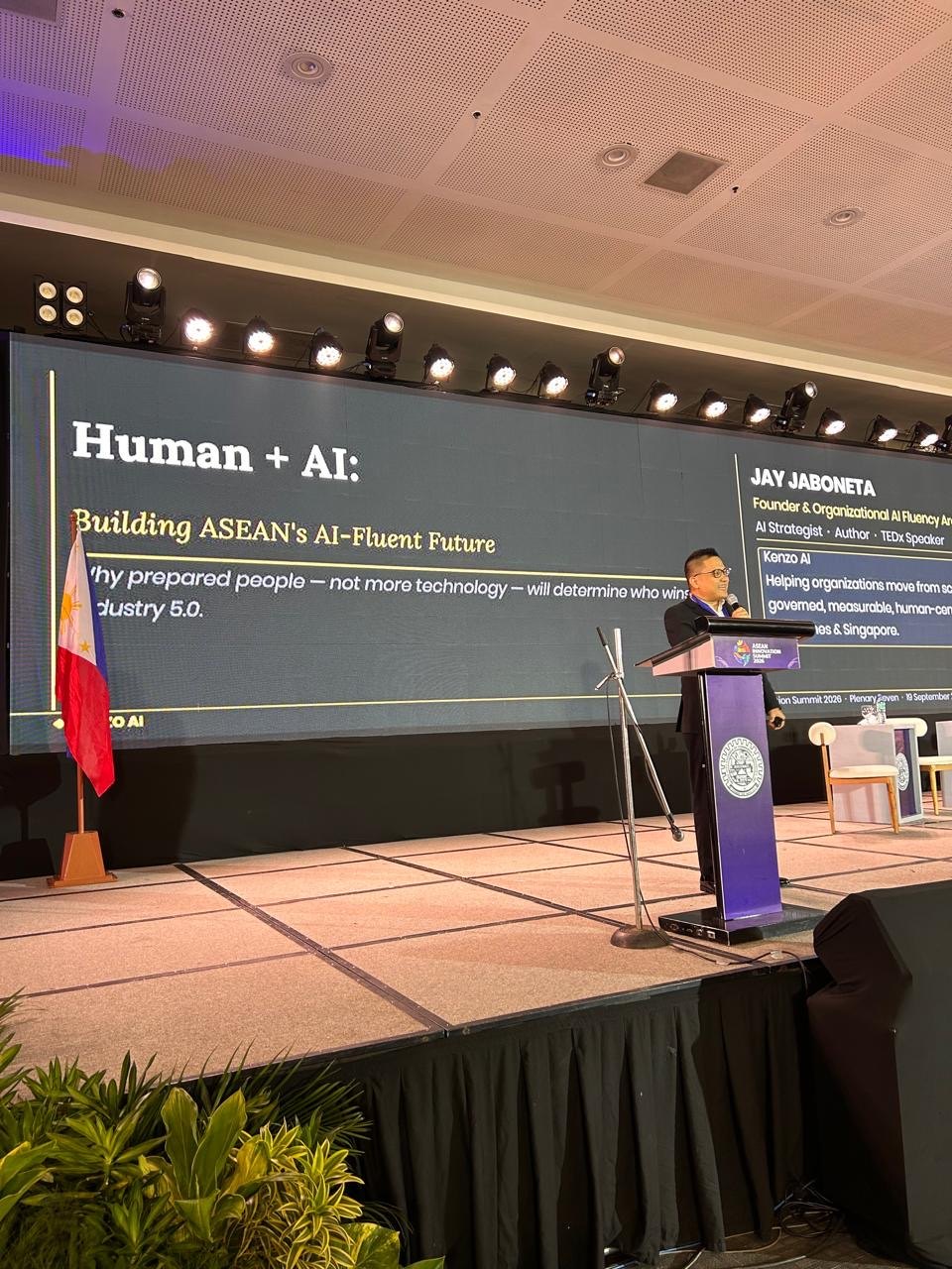 Jay Jaboneta at the podium delivering the Human + AI plenary keynote at the ASEAN Innovation Summit 2026, with his name and title on the screen behind him